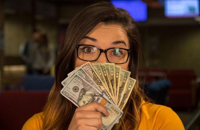 Female student with cash fanned out in front of her face.